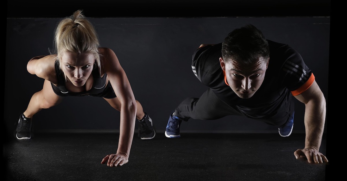 male female workout partners doing one-arm push-ups