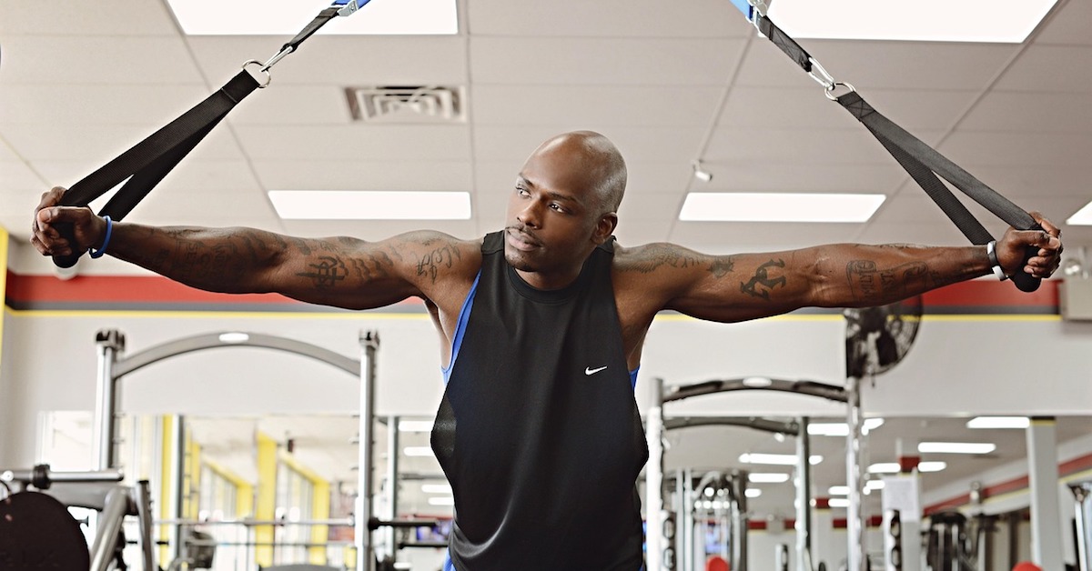 male with arms outstretched holding TRX handles